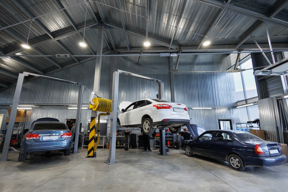 Repair of cars, chassis, automatic transmission, and engine in an auto repair shop or garage. The car is mounted on a lift.